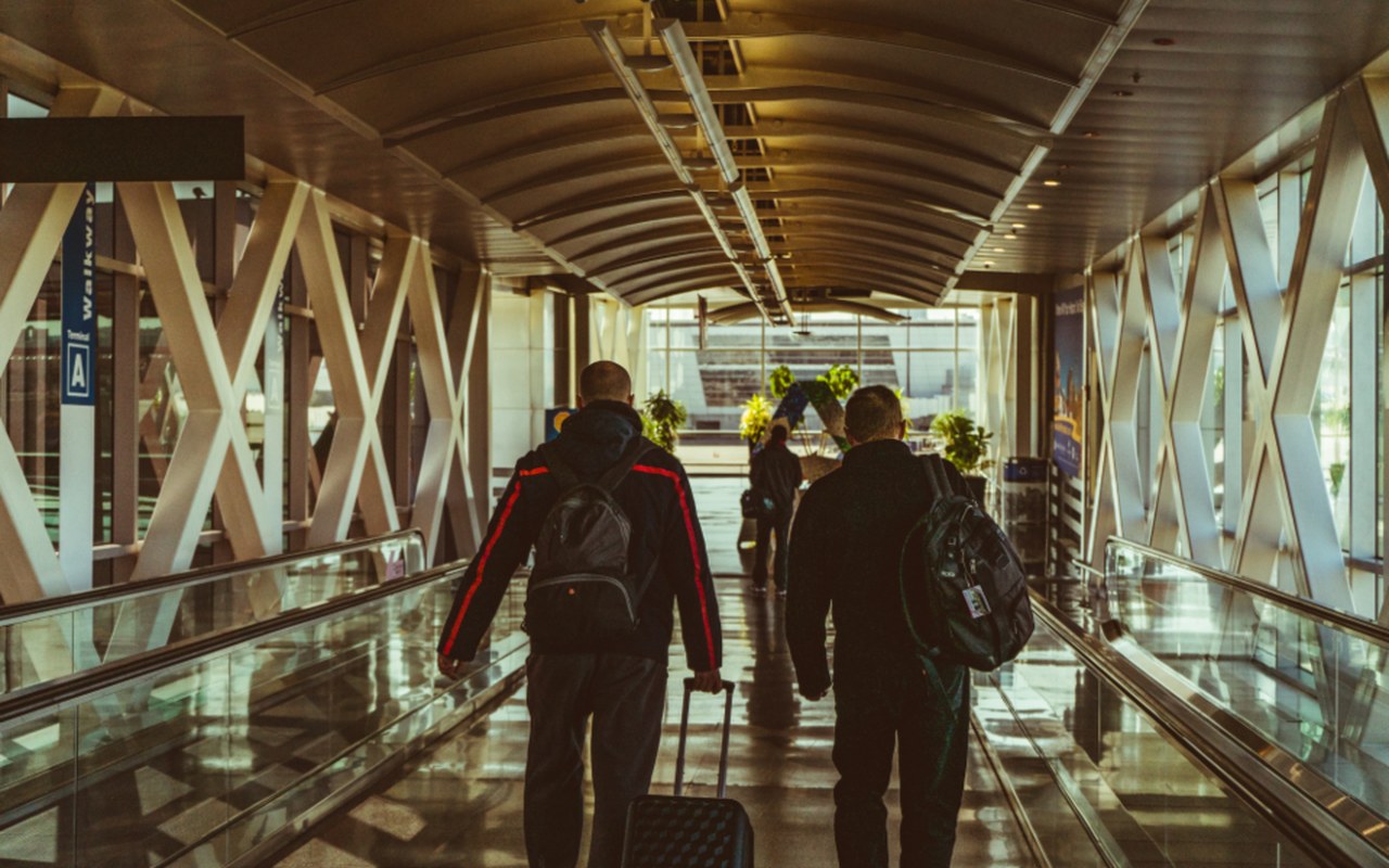 Business travellers walking down an airport boarding bridge with carry-on bags