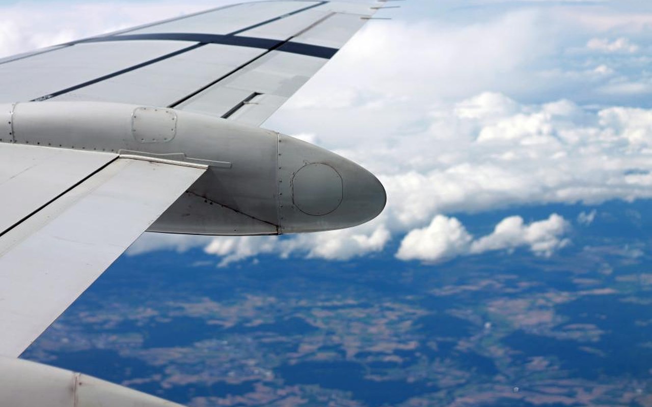 Aircraft wing above a bright bank of clouds during a long-haul flight