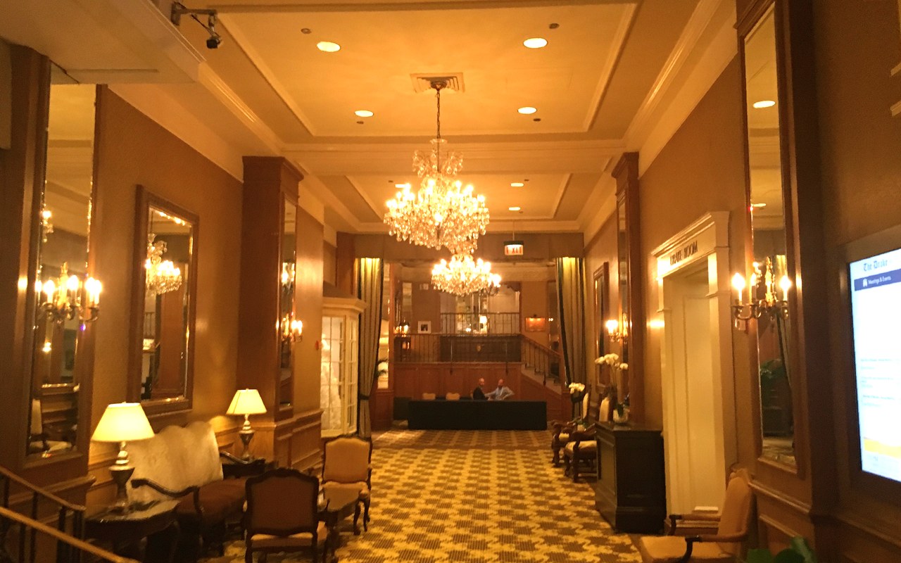 Grand hotel lobby with chandeliers, armchairs and a reception desk