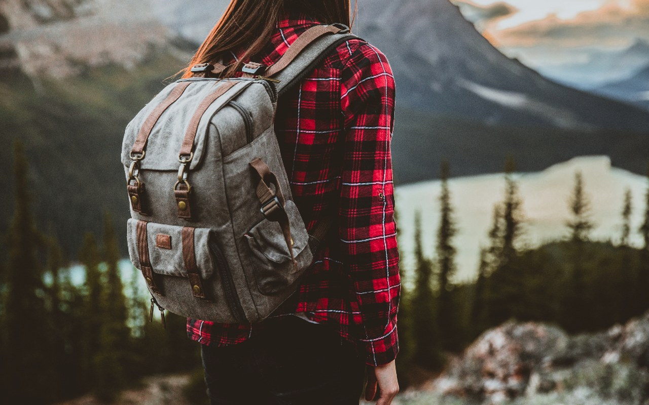 Traveller with a backpack looking out over a mountain lake